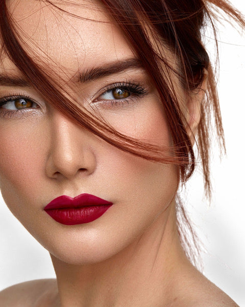 Woman with brown eyes, smooth skin and red lips. Hair falling over her face.